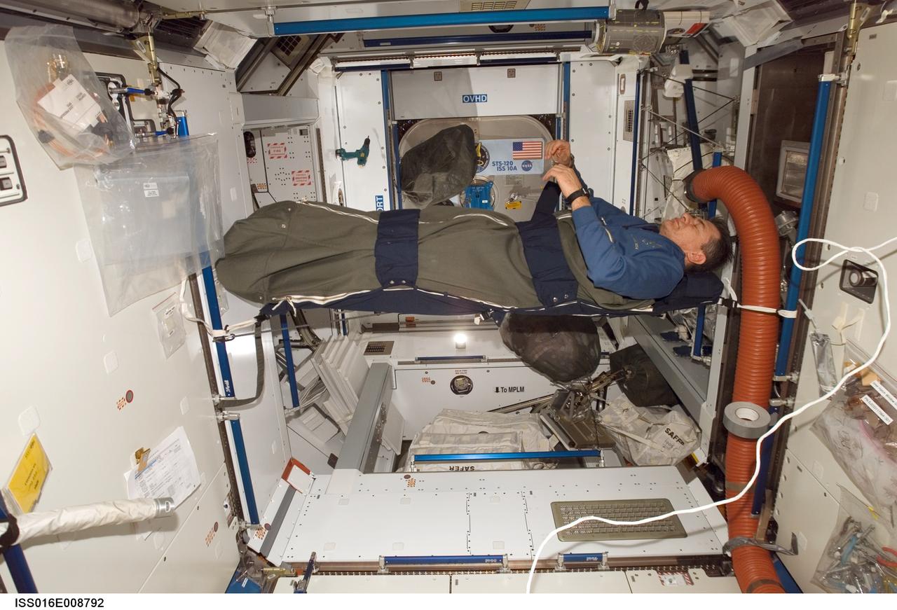 ISS016-E-008792 (2 Nov. 2007) --- European Space Agency (ESA) astronaut Paolo Nespoli, STS-120 mission specialist, rests in his sleeping bag in the Harmony node of the International Space Station while Space Shuttle Discovery is docked with the station.