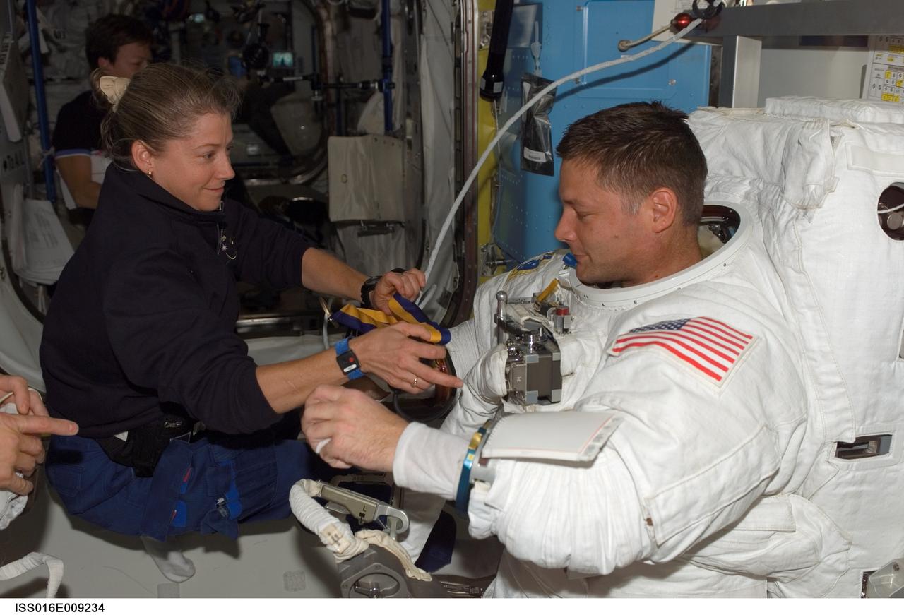 ISS016-E-009234 (3 Nov. 2007) --- Astronaut Pam Melroy, STS-120 commander, assists astronaut Doug Wheelock, mission specialist, in the removal of his Extravehicular Mobility Unit (EMU) spacesuit in the Quest Airlock of the International Space Station as the mission's fourth spacewalk draws to a close.