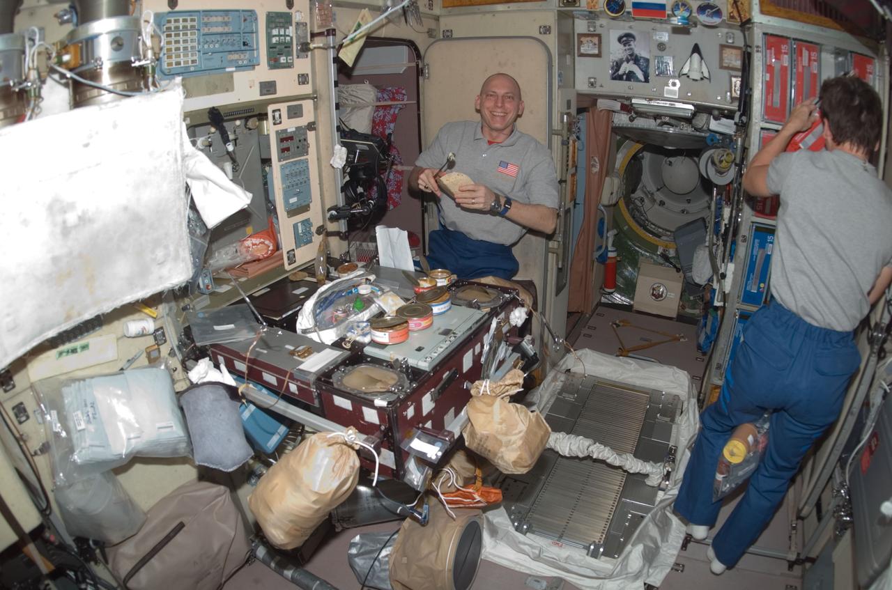 ISS016-E-009700 (4 Nov. 2007) --- Astronaut Clay Anderson, STS-120 mission specialist, prepares to eat a meal at the galley in the Zvezda Service Module of the International Space Station while Space Shuttle Discovery is docked with the station. Astronaut Peggy Whitson, Expedition 16 commander, is at right.