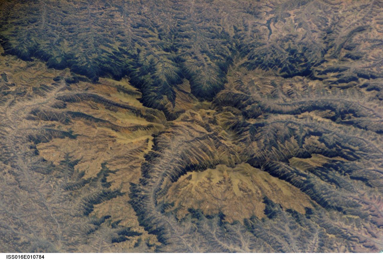 ISS016-E-010784 (16 Nov. 2007) --- Semien Mountains, Gonder, northern Ethiopia are featured in this image photographed by an Expedition 16 crewmember on the International Space Station. The Semien Mountains, the highest parts of the Ethiopian Plateau (above 2,000 meters--6,560 feet), are surrounded by a steep, ragged escarpment (step) with dramatic vertical cliffs, pinnacles, and rock spires - scenery that draws international tourists. Included in the range is the highest point in Ethiopia, Ras Dashen at 4,533 meters (14,926 feet) - an altitude only recently computed with any accuracy. The plateau and surrounding areas are made up of numerous flood basalts, totaling probably more than 3,000 meters in thickness. According to scientists, the lavas erupted quickly (in about one million years) 31 million years ago, as Ethiopia passed above what is known as the Afar "hotspot." The hotspot caused the general region of Ethiopia to be elevated, which encouraged extensive river erosion. This erosion has cut the highly dramatic canyons that ring the plateau. Although the plateau lies in the latitude of the Sahara--Arabia deserts, its great altitude makes for a cool, wet climate. This is shown by light green vegetation, compared with the brown canyons which are hot and dry. The green tinge on the biggest escarpment (trending across the top third of the image) is also vegetation, showing that this part of the escarpment also receives more rain than other parts of the escarpment wall. The Semien Mountains are one of the few places in Africa to regularly receive snow, and they receive plentiful rainfall (more than 1,280 millimeters--55 inches). A major canyon cuts the flatter plateau surface (center), with several more surrounding the plateau. These canyons are hot because they reach low altitudes, more than 2,000 meters below the plateau surface. The Semien Mountains National Park has been declared a World Heritage Site by UNESCO for its rugged beauty. In addition, several extremely rare species are found here, such as the Gelada baboon with its thick coat to protect against the cold; the critically-endangered Walia ibex with long, heavy scimitar-like horns; and the Ethiopian wolf--also known as the Semien jackal, the "most endangered canid."