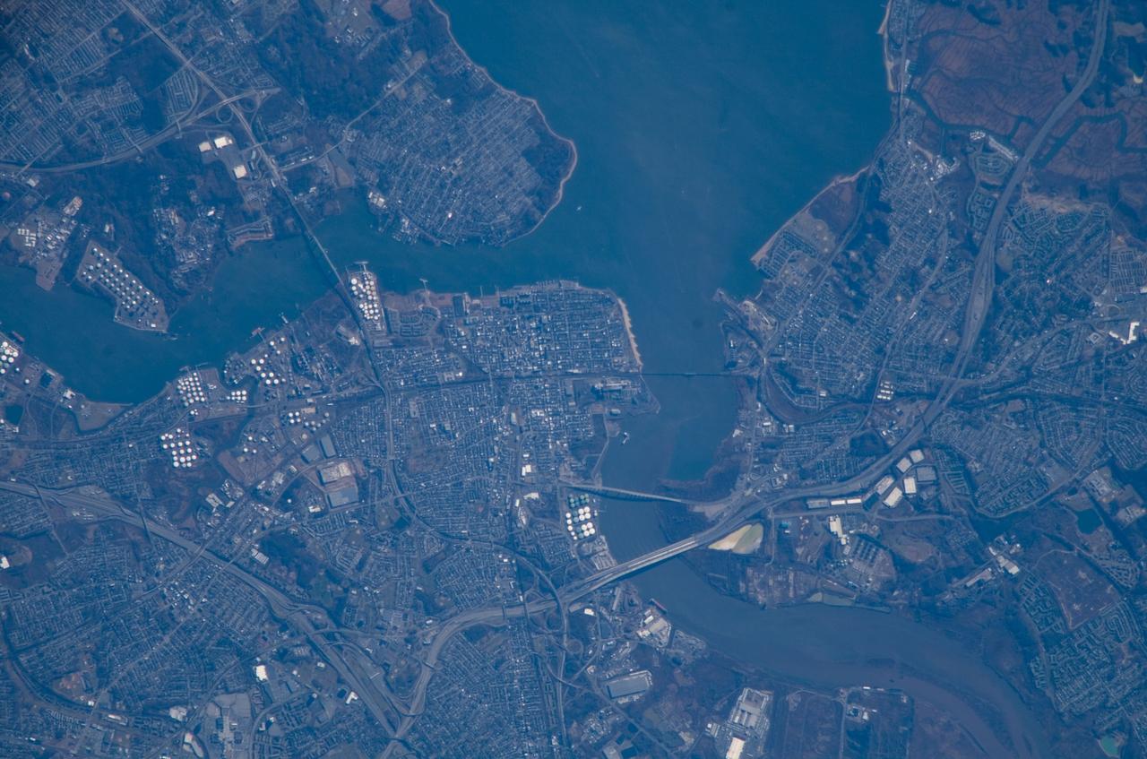 ISS016-E-018493 (24 Dec. 2007) --- Perth Amboy, New Jersey is featured in this image photographed by an Expedition 16 crewmember on the International Space Station. The port city of Perth Amboy is located between the outlets of the Raritan River and Arthur Kill ("river" in Dutch) into Raritan Bay in upper New Jersey. According to scientists, rich clay beds in the region, formed during the Cretaceous Era (approximately 65-144 million years ago), provided the raw materials for numerous pottery and terra cotta manufacturers during the 19th century. The city became an industrial and shipping center, and resort destination, through the early to mid-20th century. While the majority of the industrial factory facilities have left Perth Amboy, petroleum processing and storage remains part of the economic base -- several refining facilities are visible along the banks of Arthur Kill in this image (upper left). Originally known simply as "Amboy", "Perth" was added to the name in honor of the Earl of Perth when the city became the capital of East Jersey in 1686. Together with South Amboy across the Raritan River, both cities are collectively known today as "the Amboys". Perth Amboy is currently undergoing urban renewal and redevelopment to resume its former status of a resort destination. Raritan Bay also provides a source of local income through clam fishing.