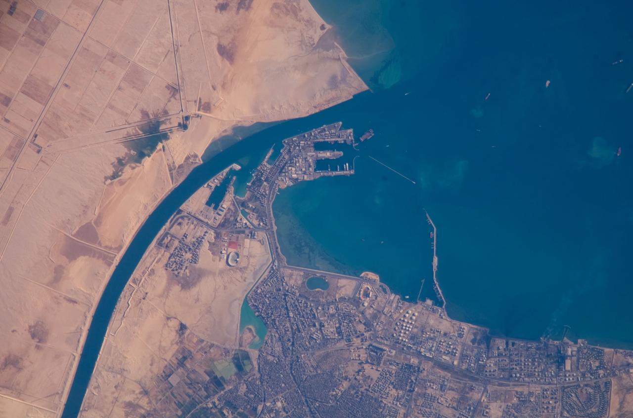 ISS016-E-019375 (30 Dec. 2007) --- Port of Suez, Egypt is featured in this image photographed by an Expedition 16 crewmember on the International Space Station. The Port of Suez is located in Egypt along the northern coastline of the Gulf of Suez. The port and city are the southern terminus of the Suez Canal that transits through Egypt and debouches into the Mediterranean Sea near Port Said. The port serves vessels transporting general cargo, oil tankers, and both commercial and private passenger vessels. The port is also an important waypoint for Muslim pilgrims traveling to and from Mecca in Saudi Arabia. Several large vessels are visible in the Gulf of Suez and berthed at various docks around the port. An extensive petroleum refinery complex forms the southern coastal boundary of the Port of Suez. At the time this image was acquired, gaseous byproducts of petroleum processing were being burned off -- as indicated by a smoke plume extending southwards into the Gulf of Suez (lower right). This view also captures several regions of greenish blue coloration in the Gulf. These are most probably sediments stirred up by passage of ships traveling to and from the Port. Similarly-colored regions along the coastline are bottom sediments visible through the shallow water column.