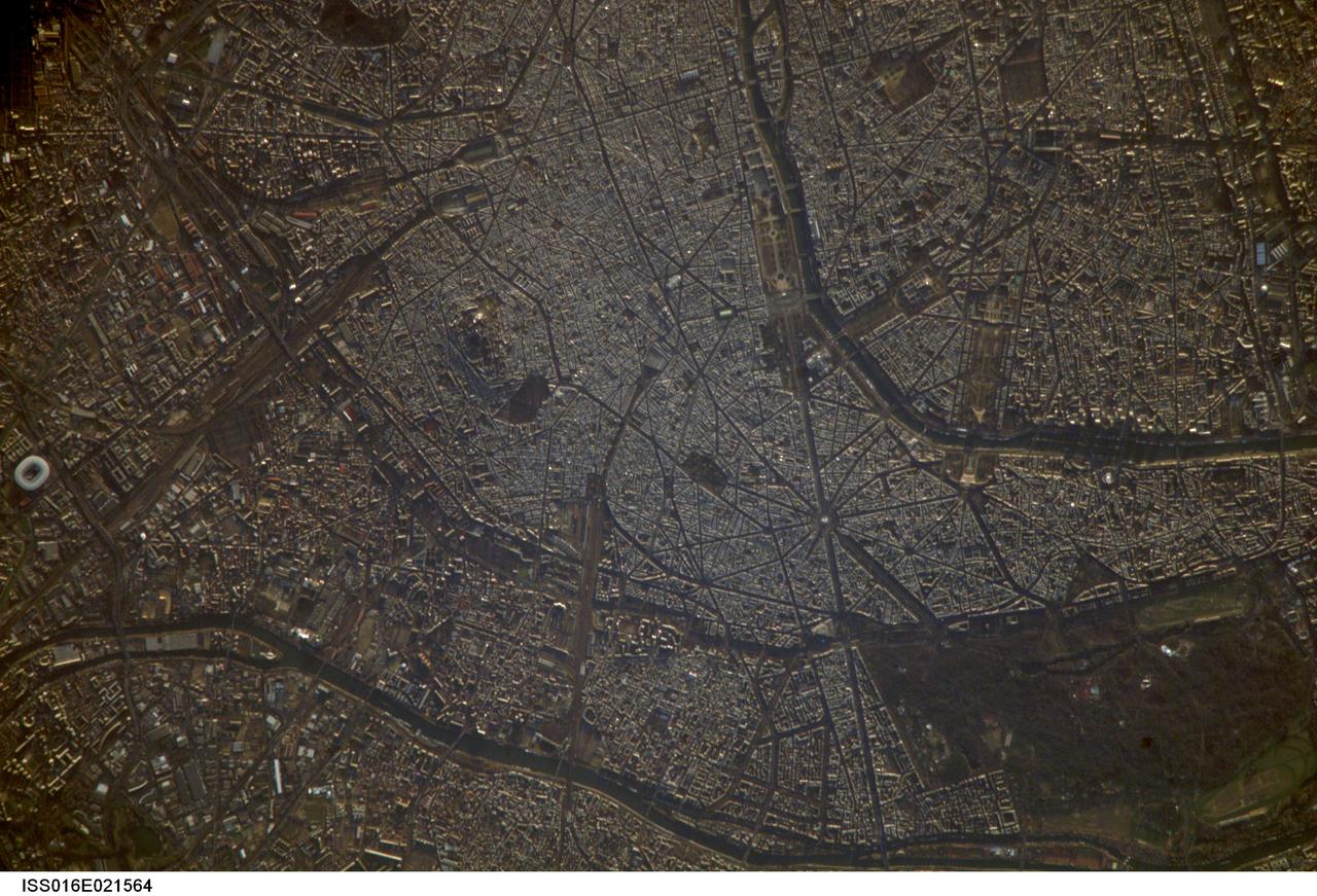 ISS016-E-021564 (7 Jan. 2008) --- Paris, France is featured in this image photographed by an Expedition 16 crewmember on the International Space Station. A crisp, clear winter day over France provided a detailed view of the city of Paris. This image shows the recognizable street pattern of the city - and some of the world's most notable landmarks - along the Seine River. One of the main avenues radiating like spokes from the Arc de Triomphe (lower right) is the Avenue des Champs-Elysees running southeast to the Garden of Tuileries (Jardin des Tuileries). The garden -- recognizable by its light green color relative to the surrounding built materials -- was originally commissioned by Catherine de Medici in 1559, and is now bounded by the Place de la Concorde to the northeast and the Louvre museum along the Seine River at the southeast end. Other, similarly colored parks and greenspaces are visible throughout the image. Farther south on the Seine is the Ile de la Cite, location of the famous Notre Dame cathedral. Perhaps most prominent is the characteristic "A" profile of the Eiffel Tower west of the Jardin des Tuileries, highlighted by morning sunlight.