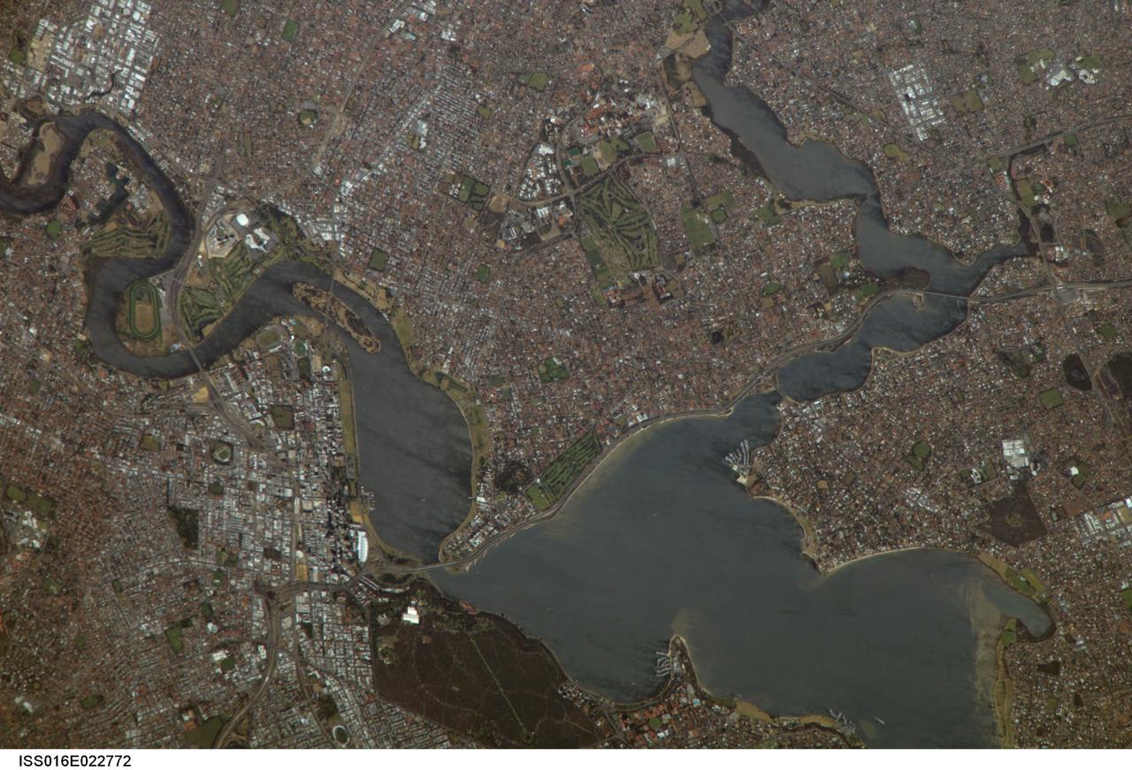 ISS016-E-022772 (11 Jan. 2008) --- Perth, Australia is featured in this image photographed by an Expedition 16 crewmember on the International Space Station (ISS). Perth is the capital of the state of Western Australia, and the largest city of the southwestern continent of Australia with an estimated population of over 1.5 million (December 2006). The downtown area of Perth and the surrounding suburbs are located on flood plain deposits of the Swan and Canning Rivers that flow through the center of the metropolitan area. Perth enjoys a Mediterranean climate, where the summers are hot and dry and winters are cool and moist. Wildfires can develop during the summer months; several large fires threatened the eastern portion of the metropolitan area in 2005. This view captures variations in urban land cover in the visible wavelengths to which the human eye is sensitive (visible red, green, and blue). The downtown center of Perth at left is characterized by large buildings (such as skyscrapers) with white reflective rooftops. Suburbs to the south (across the Swan River) are characterized by higher density of small buildings with predominantly reddish-purple roofs. Several areas of green vegetation are visible in the image. Parks and golf courses comprised mainly of grass present an even green coloration, while the dense tree canopy of Kings Park appears dark green. Variations in the coloration of the Swan and Canning Rivers is due to sunglint, or light reflected off the water surface back to the observer (in this case, a crewmember onboard the ISS).