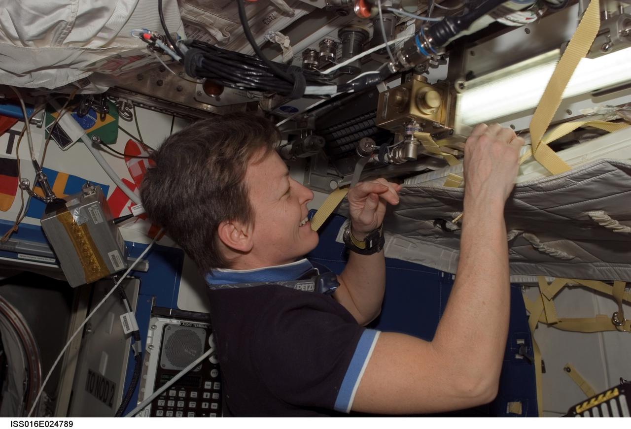 ISS016-E-024789 (18 Jan. 2008)  --- Astronaut Peggy Whitson, Expedition 16 commander, prepares to retrieve a sleep restraint device from a stowage location on the Earth-orbiting International Space Station.