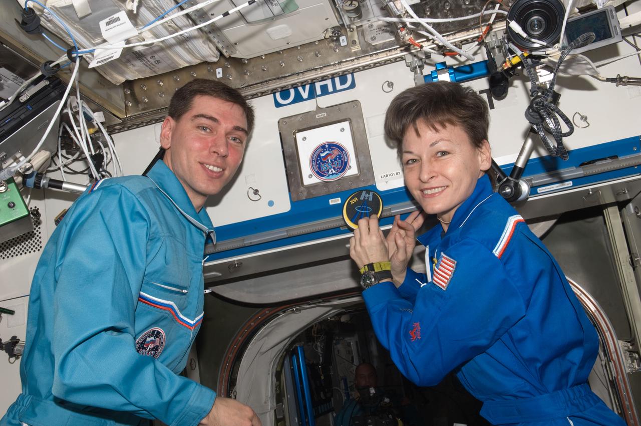 ISS016-E-036373 (17 April 2008) --- Russian Federal Space Agency cosmonaut Sergei Volkov, Expedition 17 commander; and NASA astronaut Peggy Whitson, Expedition 16 commander, pose for a photo with their mission patches in the Destiny laboratory of the International Space Station during the ceremony of Changing-of-Command from Expedition 16 to Expedition 17.