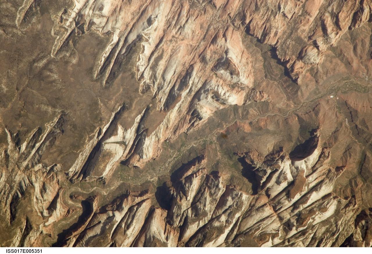 ISS017-E-005351 (26 April 2008) --- Zion National Park, Utah is featured in this image photographed by an Expedition 17 crewmember on the International Space Station. Zion National Park is located in southwestern Utah, along the western margin of the Colorado Plateau. The park was established in 1919, after roadway improvements in southwestern Utah allowed access to the preceding Mukuntuweap National Monument (1909) located in Zion Canyon. The towering cliffs bounding the North Fork of the Virgin River are formed mainly of tan to light pink Navajo Sandstone, the lithified remnants of an extensive sand dune sea that covered the area during the early Mesozoic Era, nearly 200 million years ago, according to scientists. The Zion region would have looked much like the present-day Sahara desert at this time in its geologic history. Brown rock capping the Navajo Sandstone (right) is comprised of younger beds that record changing environmental conditions that fluctuated between shallow seas and deserts. This high resolution image illustrates the incised nature of the bedrock forming the park. The long linear features are joints -- fractures in the rock mass -- formed in response to tectonic stresses that affected the region during its geologic history. The mainly north-northwest trending joints serve to channelize water runoff and are thought to be the main factor that determined the present canyon network. While the park is perhaps best experienced by hiking, backpacking, or biking, Utah State Route 9 provides automobile access up the side of Zion Canyon. The road is visible in this view as a thin brown line climbing the south wall of the canyon (lower left). Access to the rest of the park is provided by a shuttle bus system instituted in 2000 to reduce vehicle noise, improve air quality, and improve wildlife habitat.