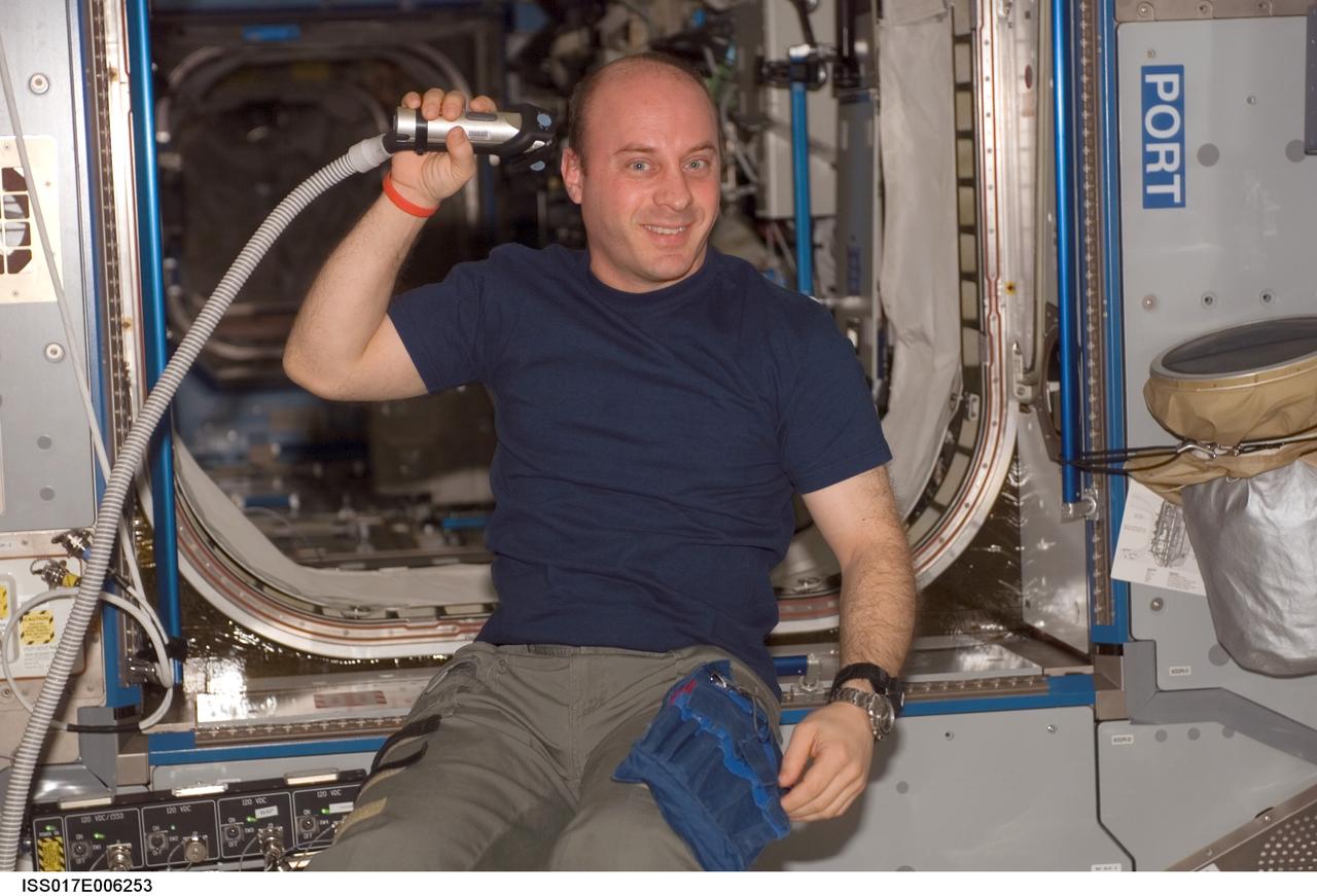 ISS017-E-006253 (4 May 2008) --- Astronaut Garrett Reisman, Expedition 17 flight engineer, trims his hair in the Harmony node of the International Space Station, using hair clippers fashioned with a vacuum device to garner freshly cut hair.