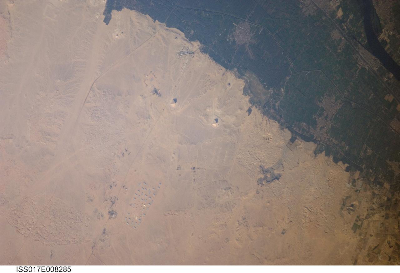 ISS017-E-008285 (30 May 2008) --- Pyramids of Dashur, Egypt are featured in this image photographed by an Expedition 17 crewmember on the International Space Station. While the pyramids of Giza are perhaps the most famous, there are several other ancient Egyptian royal necropolis ("city of the dead") sites situated along the Nile River and its delta. One of these sites is located near the village of Dashur (upper right). The gray-brown built area of Dashur is surrounded by green agricultural land of the Nile Delta, which forms a distinct boundary with the tan desert to the west. It is in the desert that the monuments of the ancient rulers of Egypt are found. Several monuments are visible in this image, including the large Red and Bent Pyramids built by Snofru, first king of the 4th Dynasty that lasted from 2575-2465 BC. Other visible monuments include the pyramid complexes of Amenemhat III and Sesostris III, both kings of the 12th Dynasty (1991-1783 BC). Both of these complexes are poorly preserved, due both to unstable ground conditions, and dismantling of the limestone blocks forming the outer pyramid casings during later historical periods. The Bent Pyramid (lower right) is so called as the slope of the outer face was lessened halfway through construction, leading to a distinctive "bent" profile -- explanations for why this was done include decreasing the mass of the pyramid to prevent collapse, or to reduce the work necessary to complete it. The Red Pyramid to the north (center) was built after the Bent Pyramid, and is named for the coloration of the building stone at the structure's core. An irregular dark feature to the southeast of the Bent Pyramid is not a shadow cast by a monument; it is an irrigation feature extending into the desert.