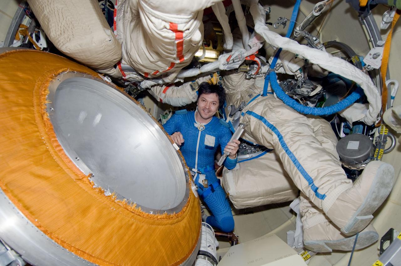 ISS017-E-010976 (10 July 2008) --- Attired in a blue thermal undergarment that complements the Russian Orlan spacesuit, Russian Federal Space Agency cosmonaut Oleg Kononenko, Expedition 17 flight engineer, holds a canister in the Pirs Docking Compartment of the International Space Station. The canister contains the pyrotechnic bolt retrieved from the Soyuz TMA-12 spacecraft during the spacewalk on July 10.