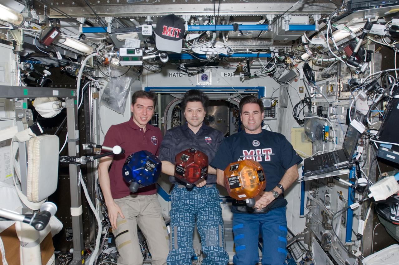 ISS017-E-015135 (30 Aug. 2008) --- Russian Federal Space Agency cosmonauts Sergei Volkov (left), Expedition 17 commander; Oleg Kononenko (center) and NASA astronaut Greg Chamitoff, both flight engineers, pose for a photo in the Destiny laboratory of the International Space Station. Three Synchronized Position Hold, Engage, Reorient, Experimental Satellites (SPHERES) float freely in the foreground.