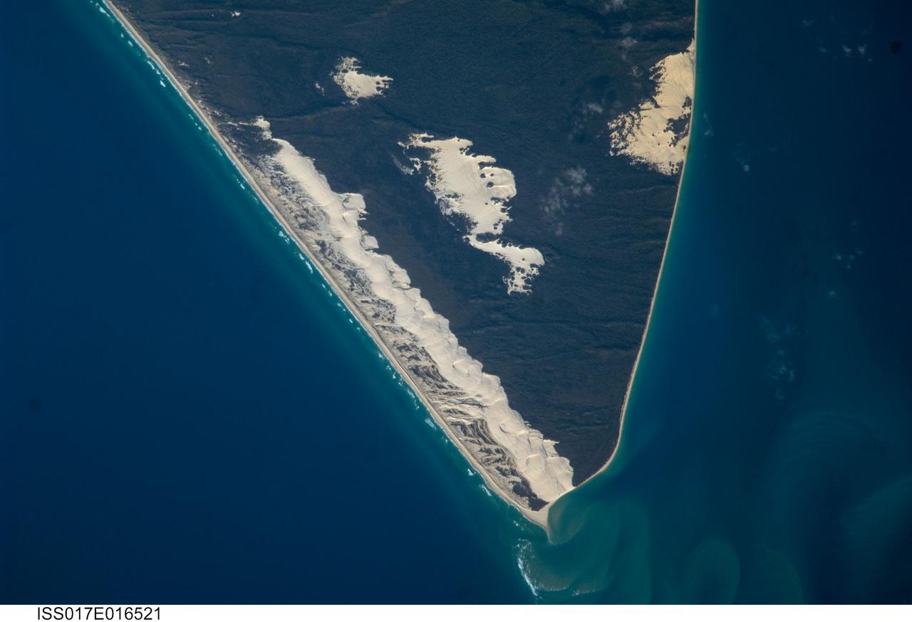 ISS017-E-016521 (15 Sept. 2008) --- Sandy Cape and Fraser Island, Australia are featured in this image photographed by an Expedition 17 crewmember on the International Space Station. Fraser Island, the world's largest sand island, includes Great Sandy National Park and is located along the coastline of Queensland, Australia. The island was designated a World Heritage site in 1992, in part due to its outstanding preservation of geological processes related to sand dune formation. According to scientists, the island's dune fields preserve a record of sand deposition and movement related to sea level rise and fall extending back over 700,000 years. In addition to sand dunes, the island also preserves an interesting range of vegetation -- including vine rainforest, stands of eucalypt trees, and mangroves -- and diverse fauna including crabs, parrots, sugar gliders and flying foxes. This view highlights the northernmost portion of the island, known as Sandy Cape. Active white sand dunes contrast with dark green vegetation that anchors older dune sets. Irregular patches of sand dunes surrounded by vegetation are known as sand blows (or blowouts), formed when the vegetation cover is disturbed -- by wind, fire, or human activities. The exposed underlying sand can then move and form new dunes, sometimes at rates of up to one meter per year. Coastal sand dune fields -- such as the one located along the eastern side of Sandy Cape (center) -- will remain active until anchored by vegetation, or until no more sand is available to form new dunes.