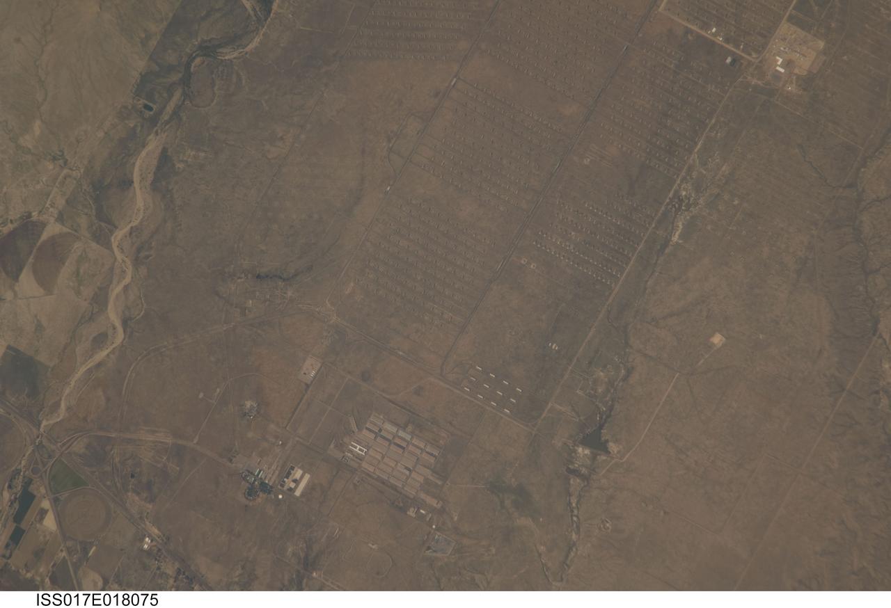 ISS017-E-018075 (1 Oct. 2008) --- The Pueblo Chemical Depot in Colorado is featured in this image photographed by an Expedition 17 crewmember on the International Space Station. This view illustrates the unusual man-made landscape of the Pueblo Chemical Depot located near the city of Pueblo, Colorado. The Depot was built during World War II by the U.S. Army to house and ship ammunition needed for war efforts, and this role transitioned to missile repair and maintenance during the Cold War with the Soviet Union. The current use of the Depot is to house chemical munitions, but changes are underway by the U.S. Army Chemical Materials Agency to destroy these munitions and make the site environmentally safe for reuse -- while also protecting the surrounding local environment. The stippled landscape pattern visible from low Earth orbit is due to hundreds of concrete and earth-covered storage "igloos" that form ordered rows across the site (top). It is within these igloos that chemical munitions and other materials are stored. Larger, white roofed maintenance buildings once used for munitions storage were built with separate compartments to minimize potential damage from explosions. Other features visible in this detailed image include linear roadway (light tan) and rail (dark brown) lines, black irregular surface impoundments of water, and various rectangular office and industrial buildings at lower left.