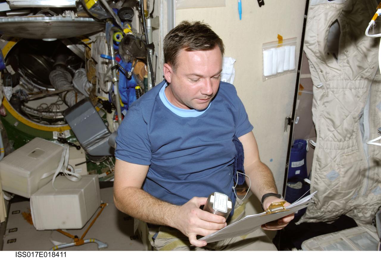 ISS017-E-018411 (15 Oct. 2008) --- Russian Federal Space Agency cosmonaut Yury Lonchakov, Expedition 18 flight engineer, looks over a procedures checklist while holding Space Science P/L Crystallizer Module-1 experiment hardware in the Zvezda Service Module of the International Space Station.