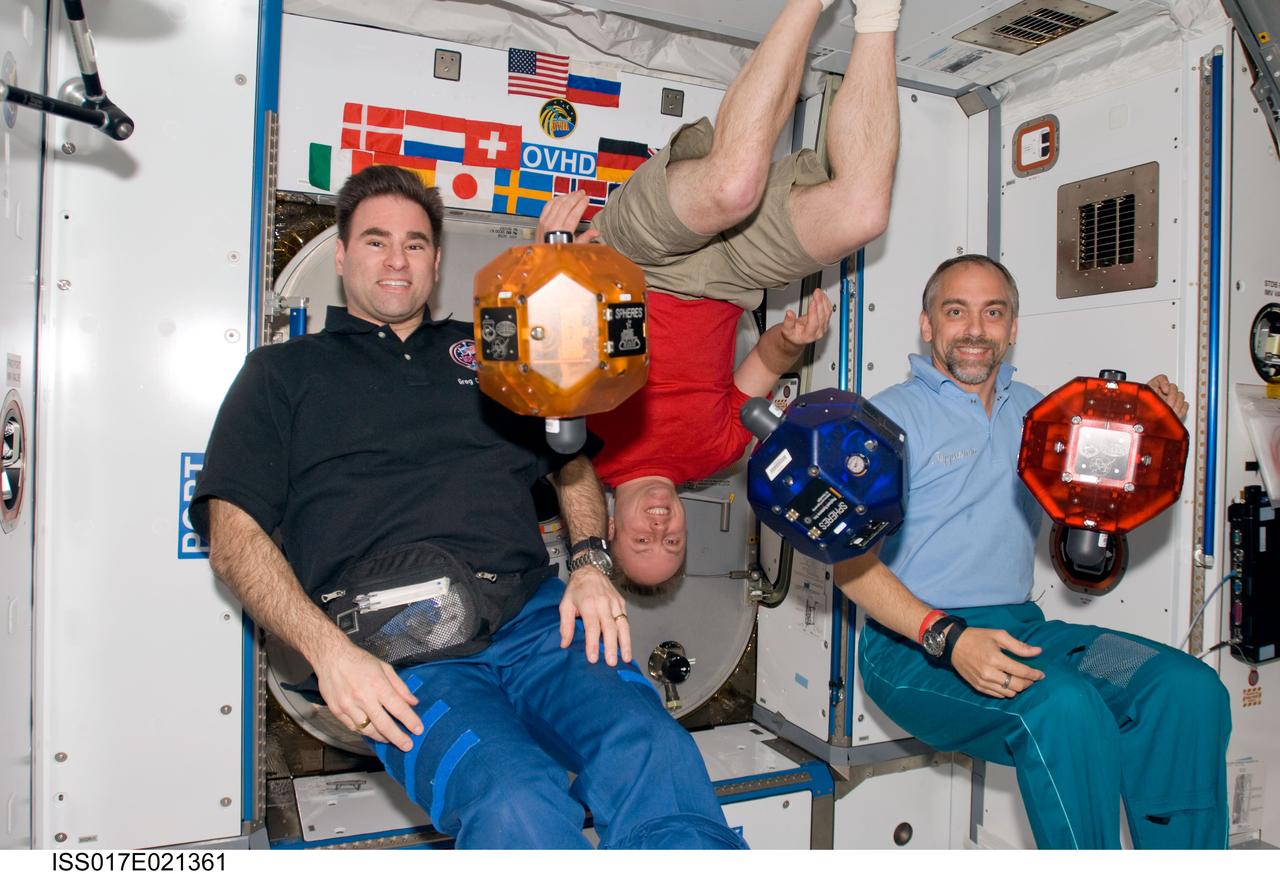 ISS017-E-021361 (22 Oct. 2008) --- Astronauts Greg Chamitoff (left), Michael Fincke, Expedition 18 flight engineer and commander, respectively; and American spaceflight participant Richard Garriott pose for a photo in the Harmony node of the International Space Station. Synchronized Position Hold, Engage, Reorient, Experimental Satellites (SPHERES) float freely in the foreground.