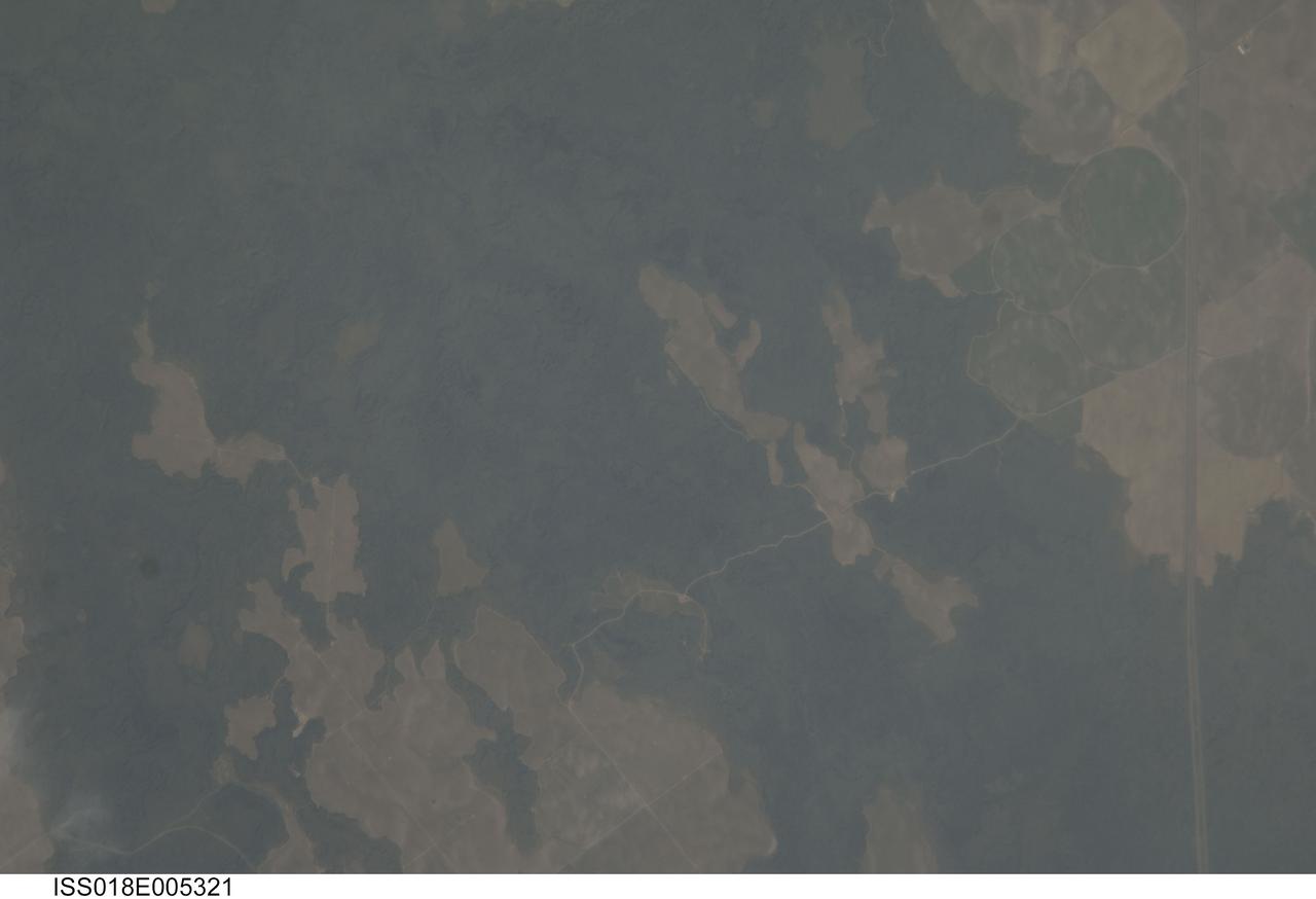 ISS018-E-005321 (24 Oct. 2008) --- The Hell's Half Acre Lava Field in Idaho is featured in this image photographed by an Expedition 18 crewmember on the International Space Station. Located in eastern Idaho, the Hell's Half Acre Lava Field is the easternmost large field associated with the Snake River Plain that arcs across the center of the state. The abundant lava flows and other volcanic rocks of the Snake River Plain are thought to be the result of southwest passage of the North American tectonic plate over a fixed mantle plume or "hotspot". According to scientists, Volcanism attributed to the hotspot began approximately 15 million years ago in the western portion of the Plain, with lava fields becoming younger to the east -- with lavas erupted approximately 4,100 years ago, Hell's Half Acre is one of the youngest lava fields. Today, the center of hotspot volcanism is located in Yellowstone National Park and feeds the extensive geyser system there. Portions of the Hell's Half Acre Lava Field are designated as a National Natural Landmark and Wilderness Study Area. This detailed photograph illustrates the forbidding landscape of the basaltic lava field -- the complex ridge patterns of the black to grey-green flow surfaces, comprised of ropy pahoehoe and blocky A a lava, are clearly visible. Regions of tan soil surrounded by lava are known as kipukas -- these "islands" are windows onto the older underlaying soil surface as they were never covered by lava. The kipukas are used for agriculture (both crops and grazing) -- several green fields are visible to the northwest of Interstate Highway 15 (right). Light to dark mottling visible in the kipukas is most likely due to variations in moisture and disturbance by agricultural activities.