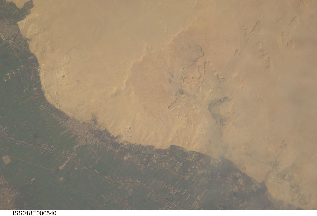 ISS018-E-006540 (31 Oct. 2008) --- Cities of the Dead and the Nile River Delta in Egypt are featured in this image photographed by an Expedition 18 crewmember on the International Space Station. The ancient pharaohs (kings) and queens of Egypt established several royal cemeteries, or necropoli (cities of the dead) along the Nile River valley. On the western bank, these cities of the dead were built on a gravelly desert plateau formed of limestone and clay overlooking the river -- several scarps are visible at upper right. The most widely recognized features of royal Egyptian necropoli are pyramids, which frequently served as both tombs and monuments for their occupants. This detailed photograph illustrates a portion of the Nile Delta that includes two royal cemetery complexes, Abusir and Saqqara-North. The present day village of Abusir is clearly visible as a grey-white irregular patch of urban materials that contrasts with adjacent green agricultural fields of the Delta and tan desert sands and gravels to the west. The historical necropolis of Abusir is located to the northwest of the village at bottom center. Three pyramids are readily visible in the image, all built by kings of the 5th Dynasty (2465--2323 BC): Sahure, Niuserre and Neferirkare. The site of Abusir was likely chosen due to the existence of a lake -- now dry -- that facilitated transport of building materials for the pyramids and other structures. The northern portion of the large necropolis of Saqqara is also visible to the south-southwest of the village of Abusir. The largest pyramid in this complex is that of Djoser, a king of the 3rd Dynasty (2650--2575 BC). Other readily visible pyramids include that of Userkaf (5th Dynasty) and Teti (6th Dynasty: 2323--2150 BC), attesting to the long history of use of the Saqqara necropolis.