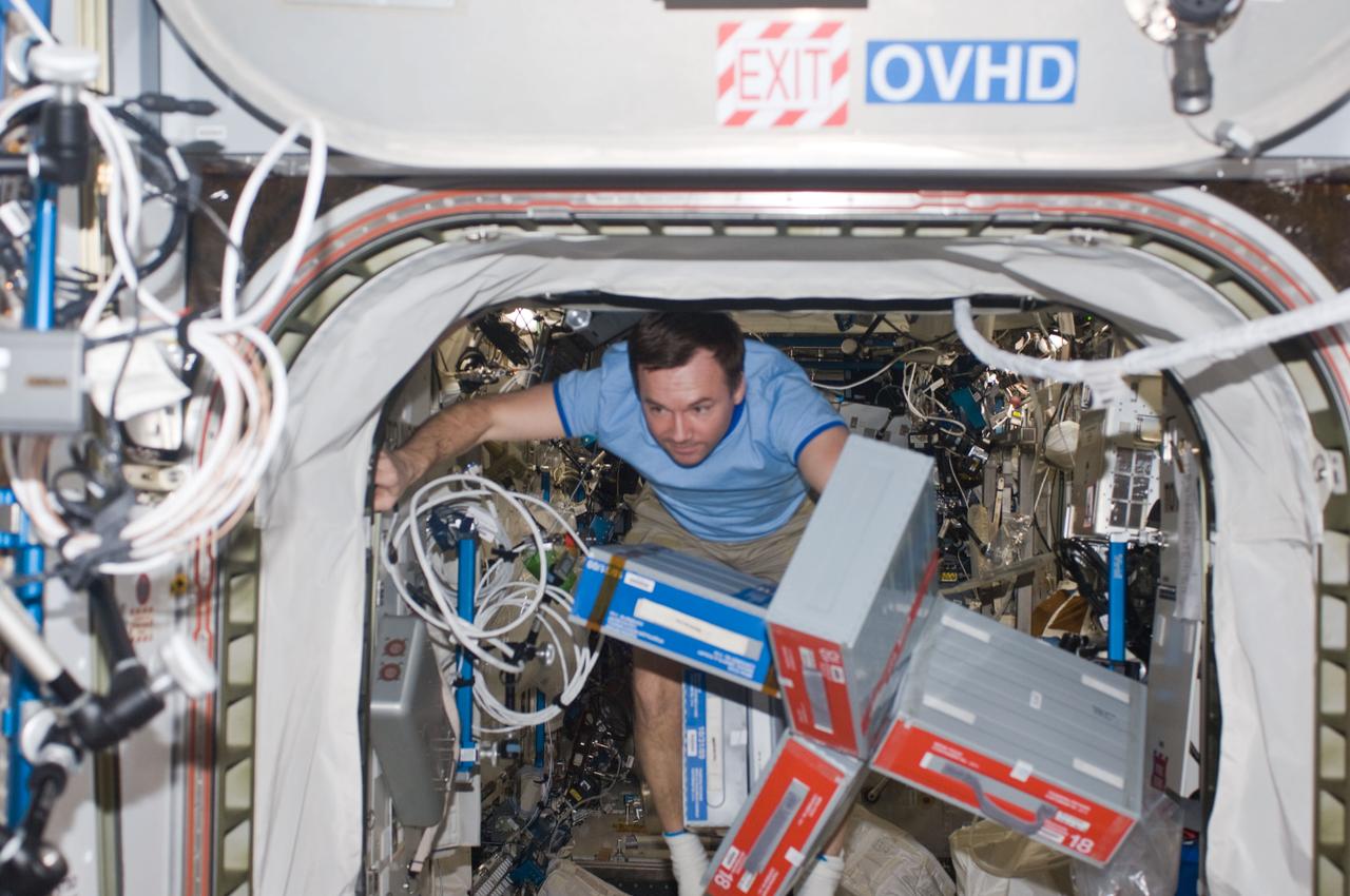 ISS018-E-009955 (2 Dec. 2008) --- Cosmonaut Yury Lonchakov, Expedition 18 flight engineer, moves storage containers through a hatch on the International Space Station.