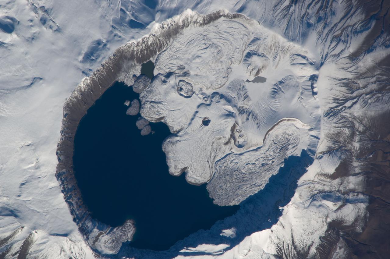ISS018-E-010206 (3 Dec. 2008) --- Mount Nemrut in Turkey is featured in this image photographed by an Expedition 18 crewmember on the International Space Station. This detailed view centers on the summit caldera of Mount Nemrut (Nemrut Dagi in Turkish), a stratovolcano located in the eastern Anatolia region of Turkey along the shoreline of Lake Van. Winter snow blankets the 2,948 meter elevation summit of the mountain, highlighting the brown caldera rim (a caldera is a large, usually circular or elliptical, collapse feature caused by the rapid emptying of an underlying magma chamber). The snow also highlights the irregular shape and wrinkled surfaces of several lava flows present in the eastern portion of the caldera. Lava flows associated with Mt. Nemrut range in composition from thin, fluid basalt to thick, glassy obsidian. A coldwater caldera lake occupies the western half of the summit. The geologic record at Mt. Nemrut indicates numerous prehistoric explosive eruptions during the Holocene Epoch ?which, according to scientists, began approximately 10,000 years ago and extends to the present day ? with eruption of lava last observed during 1441. The last well-documented explosive eruption occurred during 1650. Volcanism at Mt. Nemrut is the result of tectonic activity associated with the collision of the Arabian and Eurasian Plates; this collision is ongoing, and the presence of a warm water lake in the caldera suggests that the volcano is merely quiescent at present.