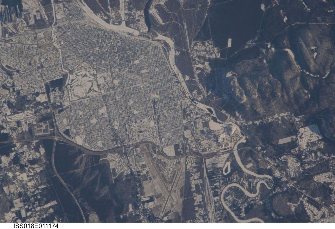 ISS018-E-011174 (6 Dec. 2008) --- The City of Thunder Bay, Ontario, Canada is featured in this image photographed by an Expedition 18 crewmember on the International Space Station. Located on the shores of Lake Superior, the metropolitan area of Thunder Bay is one of the largest in the Province of Ontario. It is also the major port providing access to the Great Lakes for central Canada?s grain products. The City of Thunder Bay is relatively new ? it was incorporated in 1970 by combining the cities of Fort William (depicted in this astronaut photograph) and Port Arthur with the townships of Neebing and McIntyre. While the growth and merging of separate municipalities into a larger contiguous metropolitan area is common (a process called agglomeration by urban geographers), it is less common for distinct cities to also merge into a new political entity. This detailed view is centered on the southern portion of Thunder Bay, comprised of the older city of Fort William. Winter snows outline the street grid of the city, while park areas interspersed throughout the street grid appear as roughly rectangular areas of unbroken white snow. Built materials appear light gray, while vegetated areas and rock outcrop near Mount McKay are dark green to dark gray. The Kam River to the south of Fort William is ice-covered, and has a homogeneous covering of snow that traces the river channel.