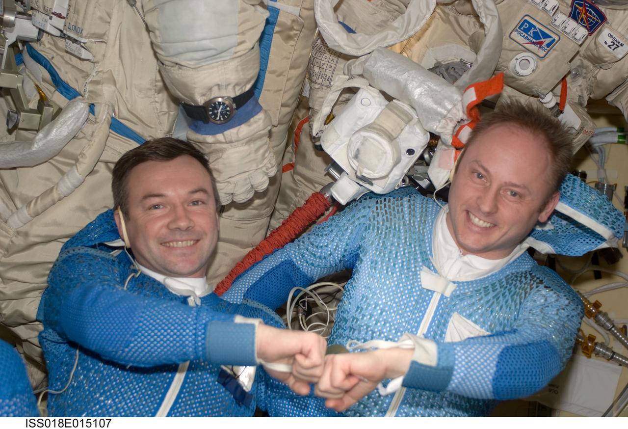 ISS018-E-015107 (22 Dec. 2008) --- Astronaut Michael Fincke (right) and cosmonaut Yury Lonchakov, Expedition 18 commander and flight engineer, respectively, pose for a photo with their Russian Orlan spacesuits in the Pirs Docking Compartment of the International Space Station during preparations for the Dec. 23 spacewalk.