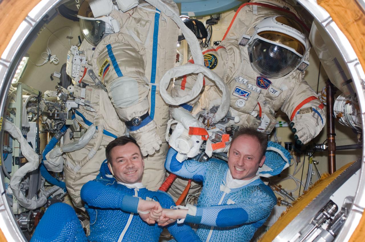ISS018-E-015110 (22 Dec. 2008) --- Astronaut Michael Fincke (right) and cosmonaut Yury Lonchakov, Expedition 18 commander and flight engineer, respectively, pose for a photo with their Russian Orlan spacesuits in the Pirs Docking Compartment of the International Space Station during preparations for the Dec. 23 spacewalk.