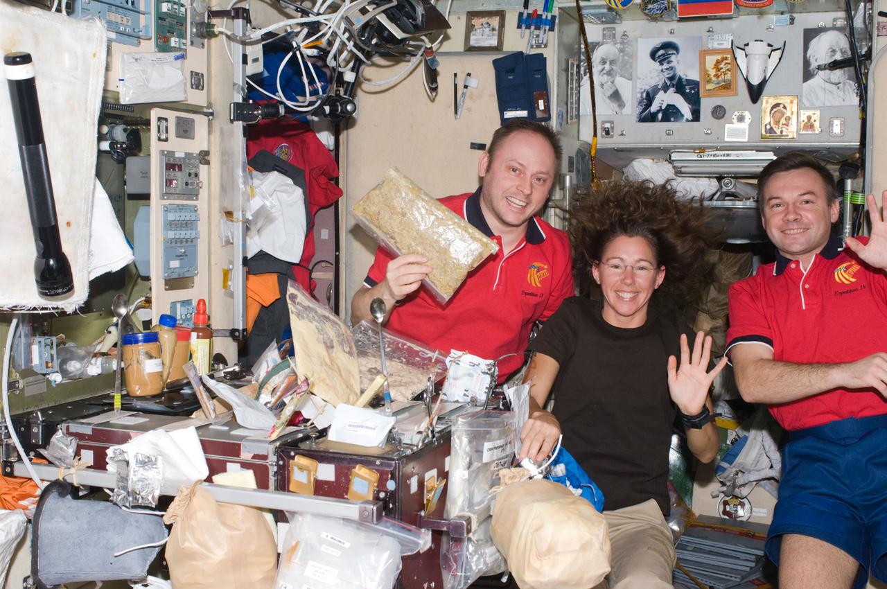 ISS018-E-015379 (25 Dec. 2008) --- Astronauts Michael Fincke (left), Expedition 18 commander; Sandra Magnus and cosmonaut Yury Lonchakov, both flight engineers, pose for a photo as they prepare to share a Christmas meal at the galley in the Zvezda Service Module of the International Space Station.