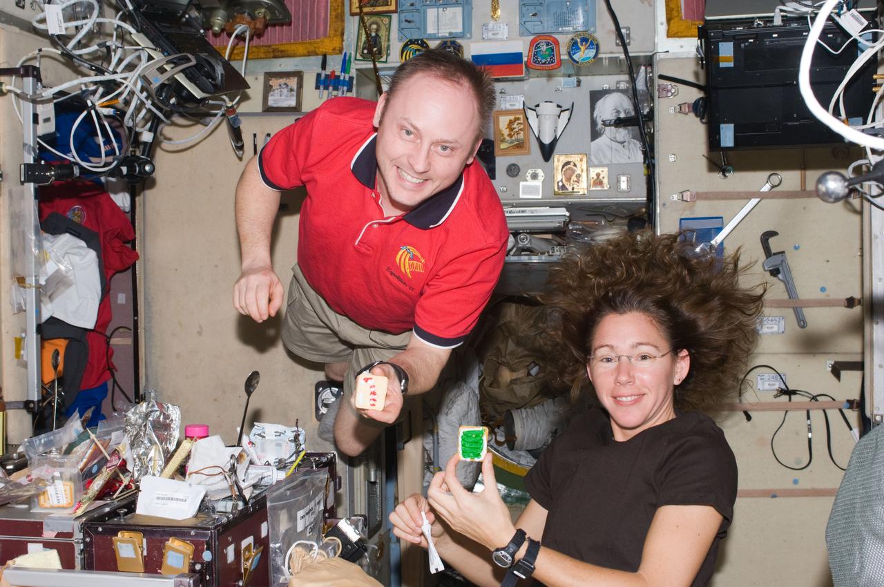 ISS018-E-015394 (25 Dec. 2008) --- Astronauts Michael Fincke, Expedition 18 commander, and Sandra Magnus, flight engineer, hold Christmas cookies while posing for a photo near the galley in the Zvezda Service Module of the International Space Station.