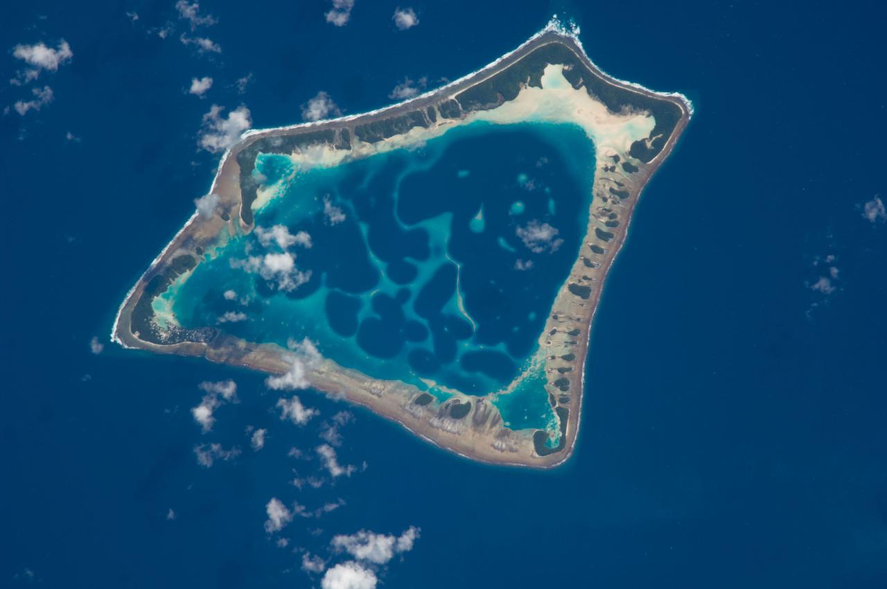 ISS018-E-018129 (6 Jan. 2009) --- Atafu Atoll in the Southern Pacific Ocean is featured in this image photographed by an Expedition 18 crewmember on the International Space Station. At roughly eight kilometers wide, Atafu Atoll is the smallest of three atolls (with Nukunonu and Fakaofo atolls to the southeast, not shown) comprising the Tokelau Islands group located in the southern Pacific Ocean. Swains Island to the south (not shown) is also considered part of the Tokelau group. The political entity of Tokelau is currently a territory of New Zealand. In recent years, public referendums on independence within the islands have been held, but have not received sufficient support to move forward. The primary settlement on Atafu is a village located at the northwestern corner of the atoll ? indicated by an area of light gray dots in this photograph. The typical ring shape of the atoll is the result of coral reefs building up around a former volcanic island. Over geologic time, the central volcano has subsided beneath the water surface, leaving the fringing reefs and a central lagoon that contains submerged coral reefs. Erosion and soil development on the surfaces of the exposed fringing reefs has lead to formation of tan to light brown beach deposits (southern and western sides of the atoll) and green vegetation cover (northern and eastern sides of the atoll). The Tokelau Islands, including Atafu Atoll, suffered significant inundation and erosion during Tropical Cyclone Percy in 2005. The approximate elevation of Atafu Atoll is only two meters above the tidal high water level. Vulnerability to tropical cyclones and potential sea level rise makes the long-term habitability of the atoll uncertain.