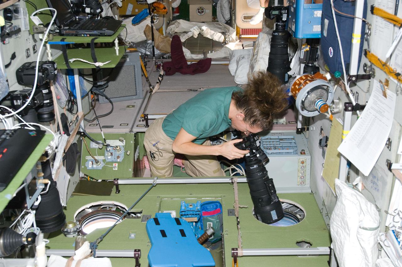 ISS018-E-029159 (9 Feb. 2009) --- Astronaut Sandra Magnus, Expedition 18 flight engineer, uses a still camera at a window in the Zvezda Service Module of the International Space Station.