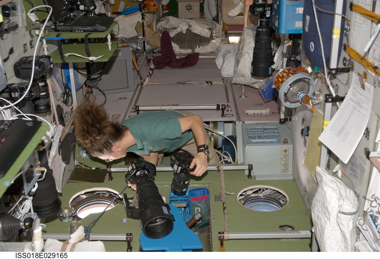ISS018-E-029165 (9 Feb. 2009) --- Astronaut Sandra Magnus, Expedition 18 flight engineer, holds two still cameras while looking through a window in the Zvezda Service Module of the International Space Station.