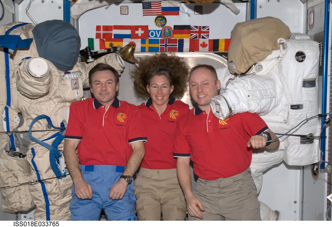 ISS018-E-033765 (19 Feb. 2009) --- Astronaut Michael Fincke (right), Expedition 18 commander; astronaut Sandra Magnus and cosmonaut Yury Lonchakov, both flight engineers, pose for a crew photo between a Russian Orlan spacesuit and an Extravehicular Mobility Unit (EMU) spacesuit in the Harmony node of the International Space Station.