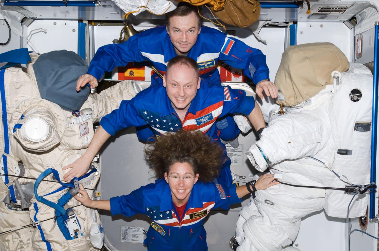 ISS018-E-033778 (19 Feb. 2009) --- Astronaut Michael Fincke (center), Expedition 18 commander; astronaut Sandra Magnus and cosmonaut Yury Lonchakov, both flight engineers, pose for a crew photo between a Russian Orlan spacesuit and an Extravehicular Mobility Unit (EMU) spacesuit in the Harmony node of the International Space Station.