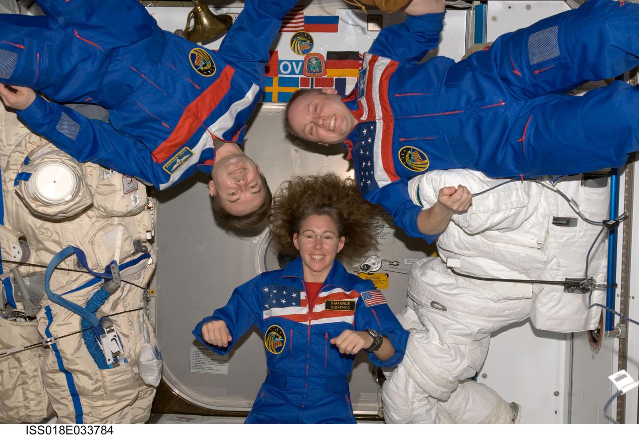 ISS018-E-033784 (19 Feb. 2009) --- Astronaut Michael Fincke (right), Expedition 18 commander; astronaut Sandra Magnus and cosmonaut Yury Lonchakov, both flight engineers, pose for a crew photo between a Russian Orlan spacesuit and an Extravehicular Mobility Unit (EMU) spacesuit in the Harmony node of the International Space Station.