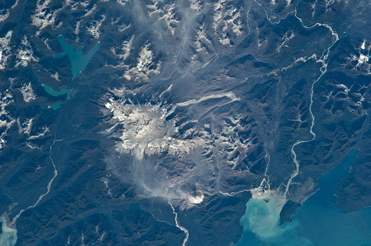 ISS018-E-035716 (24 Feb. 2009) --- Minchinmavida and Chaiten Volcanoes in Chile are featured in this image photographed by an Expedition 18 crewmember on the International Space Station. The Andes mountain chain along the western coastline of South America includes numerous active stratovolcanoes. The majority of these volcanoes are formed, and fed, by magma generated as the oceanic Nazca tectonic plate moves northeastward and plunges beneath the less dense South American continental tectonic plate (a process known as subduction). The line of Andean volcanoes marks the approximate location of the subduction zone. This astronaut photograph highlights two volcanoes located near the southern boundary of the Nazca ? South America subduction zone in southern Chile. Dominating the scene is the massive Minchinmavida stratovolcano at center. An eruption of this glaciated volcano was observed by Charles Darwin during his Galapagos Island voyage in 1834; the last recorded eruption took place the following year. The white, snow covered summit of Minchinmavida is blanketed by gray ash erupted from its much smaller but now active neighbor to the west, Volcan (volcano) Chaiten. The historically inactive Chaiten volcano, characterized by a large lava dome within a caldera (an emptied and collapsed magma chamber beneath a volcano) roared back to life unexpectedly on May 2, 2008, generating dense ash plumes and forcing the evacuation of the nearby town of Chaiten. Volcanic activity continues at Chaiten, including partial collapse of a new lava dome and generation of a pyroclastic flow several days before this photograph was taken. A steam and ash plume is visible extending to the northeast from the eruptive center of the volcano.