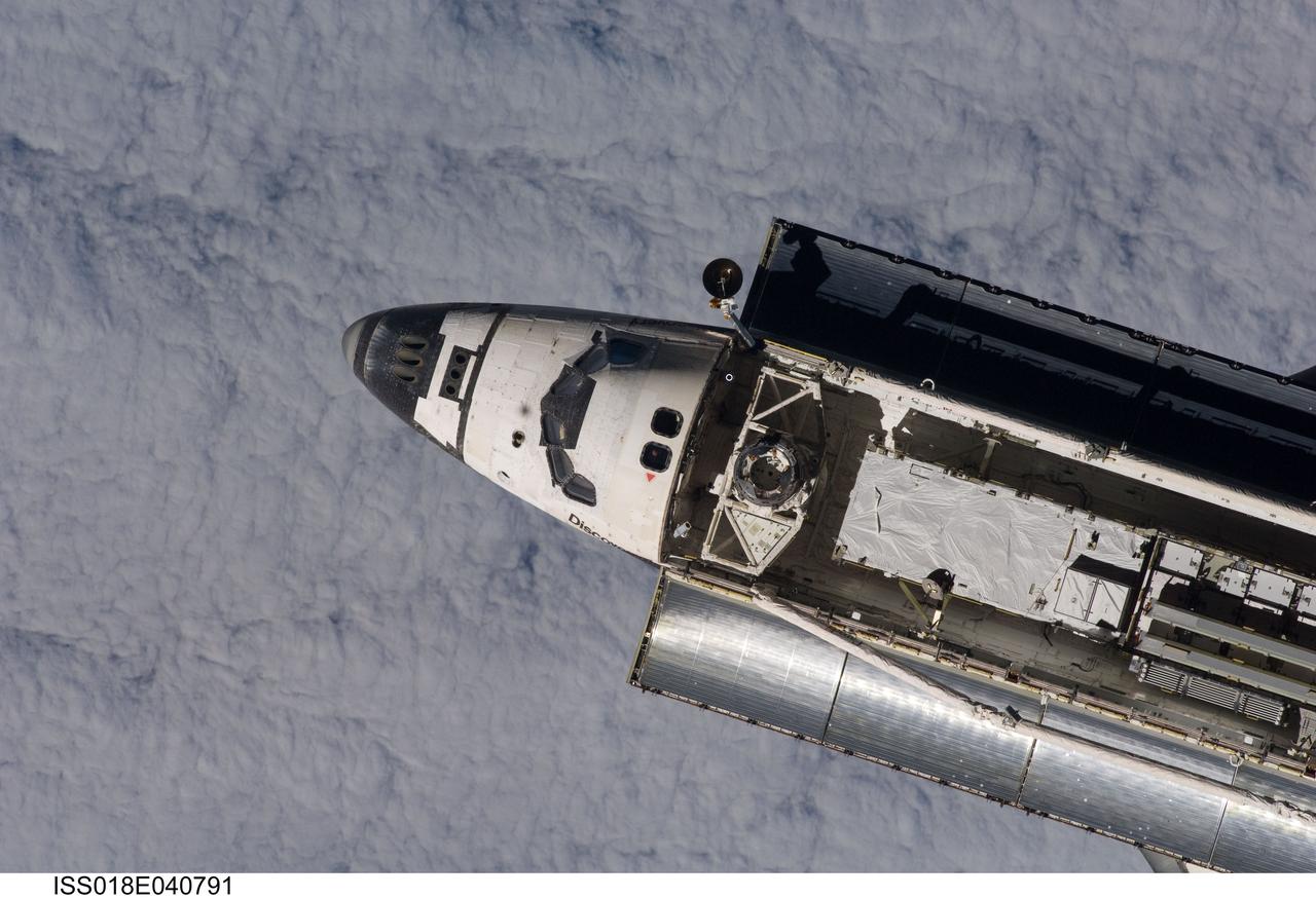 ISS018-E-040791 (17 March 2009) --- Backdropped by a blanket of clouds, Space Shuttle Discovery is featured in this image photographed by an Expedition 18 crewmember on the International Space Station during rendezvous and docking operations. Before docking with the station, astronaut Lee Archambault, STS-119 commander, flew the shuttle through a Rendezvous Pitch Maneuver or basically a backflip to allow the space station crew a good view of Discovery's heat shield. Using digital still cameras equipped with both 400 and 800 millimeter lenses, the ISS crewmembers took a number of photos of the shuttle's thermal protection system and sent them down to teams on the ground for analysis. A 400 millimeter lens was used for this image. Docking occurred at 4:20 p.m. (CDT) on March 17, 2009. The final pair of power-generating solar array wings and the S6 truss segment are visible in Discovery?s cargo bay.