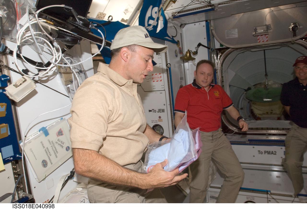 ISS018-E-040998 (18 March 2009) --- Astronauts Lee Archambault (left), STS-119 commander; Michael Fincke, Expedition 18 commander; and Tony Antonelli (partially out of frame at right), STS-119 pilot, are pictured in the Harmony node of the International Space Station while Space Shuttle Discovery remains docked with the station.
