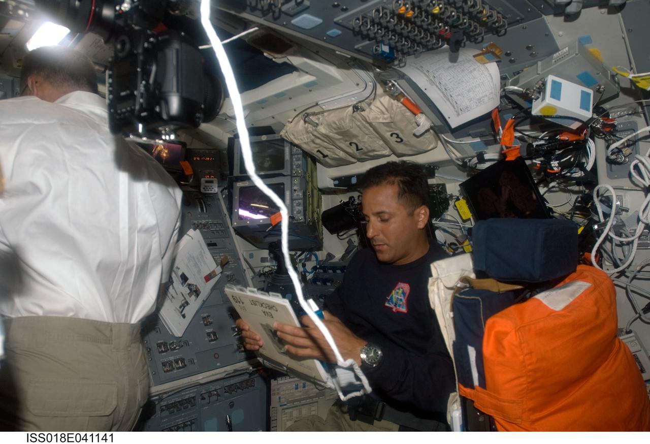 ISS018-E-041141 (19 March 2009) --- Astronaut Joseph Acaba (right), STS-119 mission specialist, looks over a checklist on the flight deck of Space Shuttle Discovery while docked with the International Space Station. Astronaut Lee Archambault, commander, is at left.