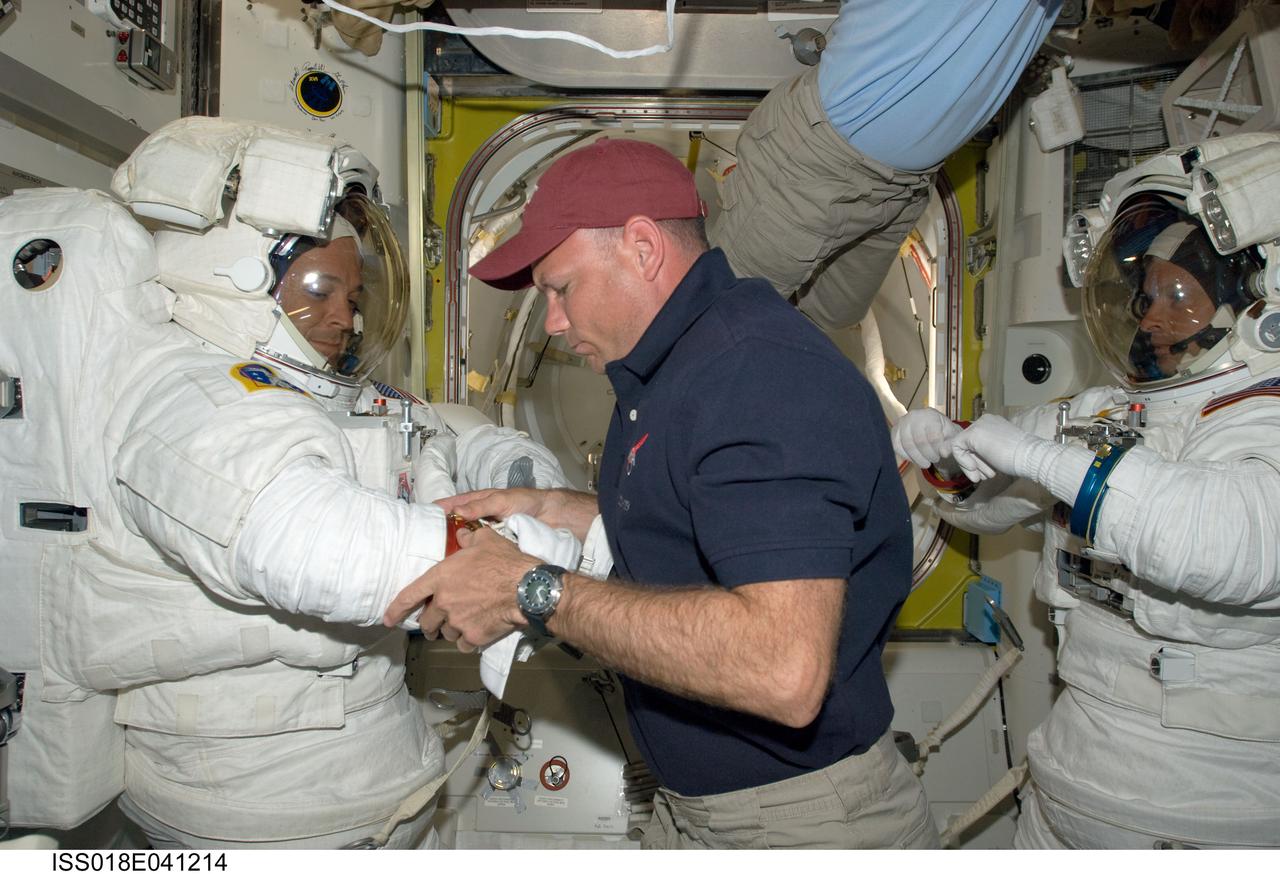 ISS018-E-041214 (19 March 2009) --- Astronauts Steve Swanson (right) and Richard Arnold, both STS-119 mission specialists, attired in their Extravehicular Mobility Unit (EMU) spacesuits, are pictured in the Quest Airlock of the International Space Station as the mission's first scheduled session of extravehicular activity (EVA) draws to a close. Astronauts Michael Fincke (partially out of frame), Expedition 18 commander; and Tony Antonelli, STS-119 pilot, assist with the doffing of the spacesuits.