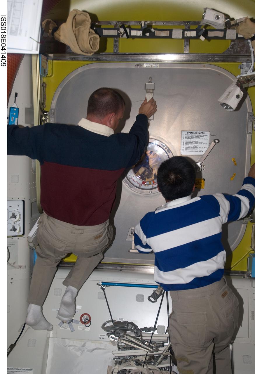 ISS018-E-041409 (21 March 2009) --- Astronaut Tony Antonelli (left), STS-119 pilot; and Japan Aerospace Exploration Agency (JAXA) astronaut Koichi Wakata, Expedition 18 flight engineer, prepare to open the hatch door in the Quest Airlock of the International Space Station for the returning spacewalkers as the mission?s second session of extravehicular activity (EVA) draws to a close.
