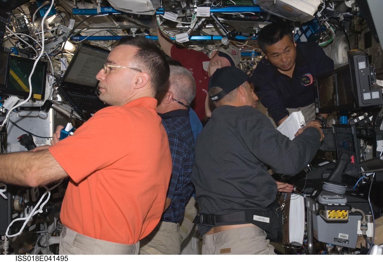 ISS018-E-041495 (20 March 2009) --- Crewmembers on the International Space Station are busy with various tasks in the Destiny laboratory while Space Shuttle Discovery remains docked with the station. Pictured (from the left) are astronauts Lee Archambault, STS-119 commander; John Phillips, Richard Arnold (mostly obscured) and Steve Swanson, all STS-119 mission specialists; along with astronaut Michael Fincke (top center), Expedition 18 commander; and Japan Aerospace Exploration Agency (JAXA) astronaut Koichi Wakata (top right), Expedition 18 flight engineer.