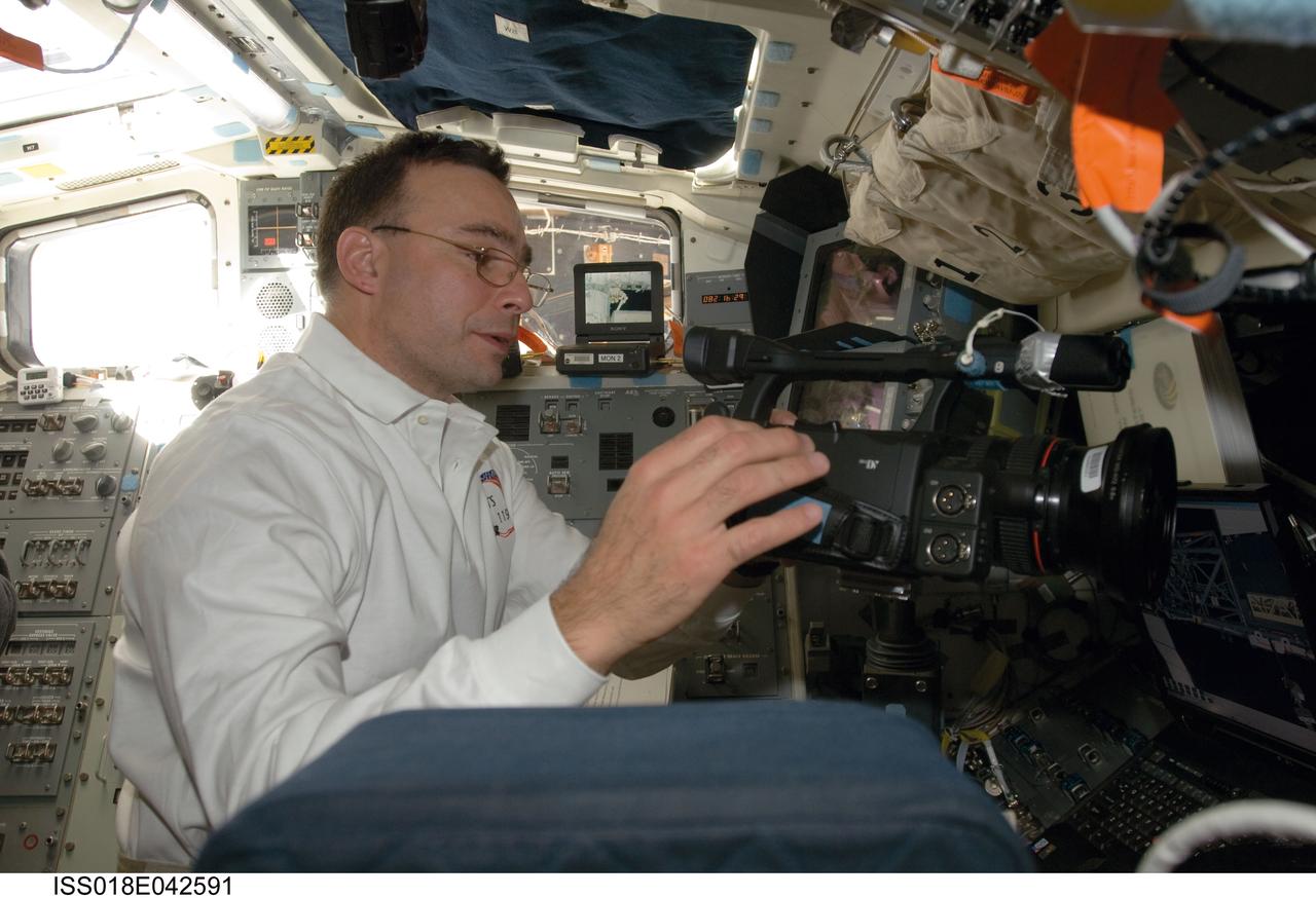 ISS018-E-042591 (23 March 2009) --- Astronaut Lee Archambault, STS-119 commander, uses a video camera on the flight deck of Space Shuttle Discovery while docked with the International Space Station.