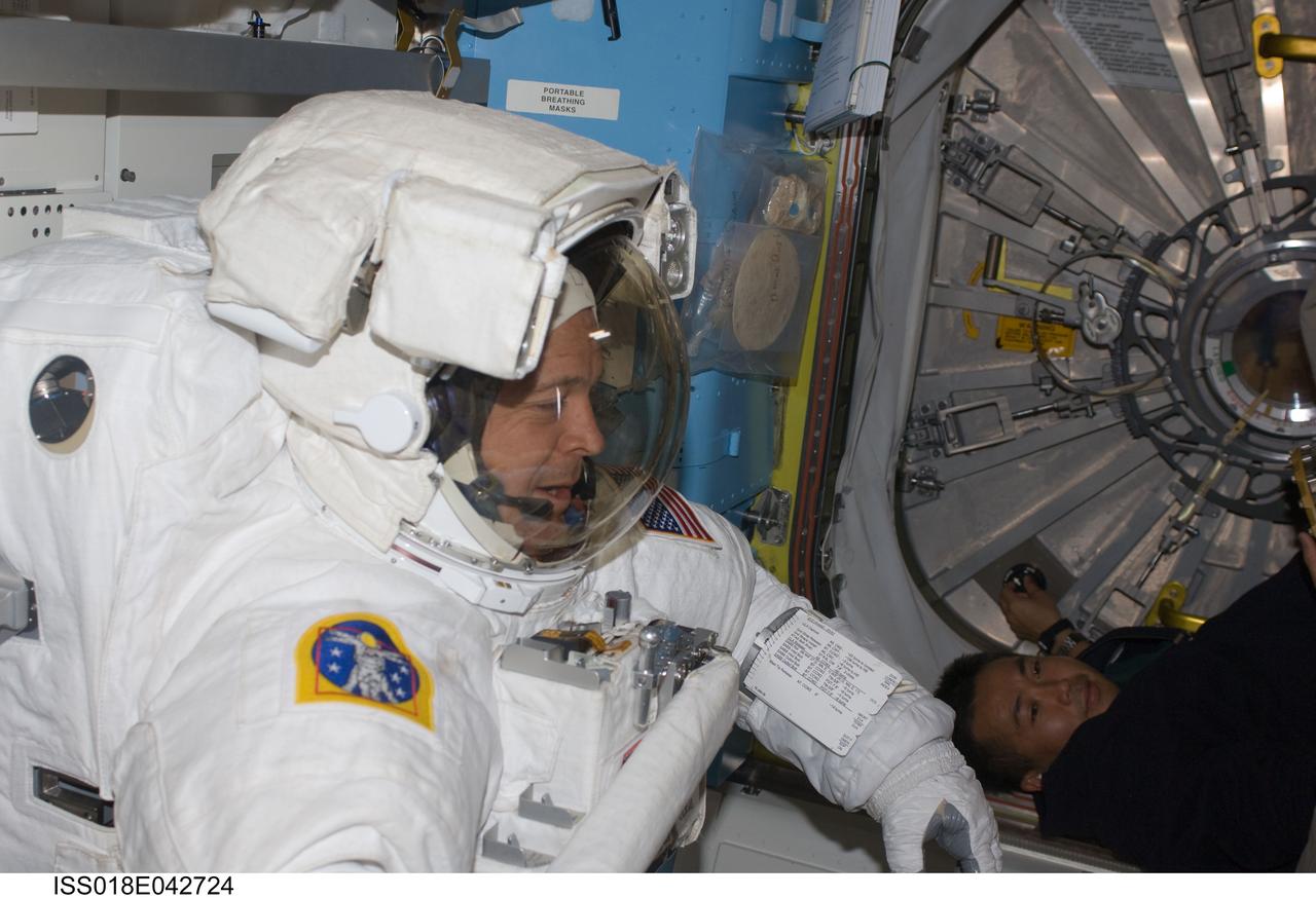 ISS018-E-042724 (23 March 2009) --- Astronaut Richard Arnold, STS-119 mission specialist, attired in his Extravehicular Mobility Unit (EMU) spacesuit, is pictured in the Quest Airlock of the International Space Station as he prepares for the mission's third scheduled session of extravehicular activity (EVA). Japan Aerospace Exploration Agency (JAXA) astronaut Koichi Wakata, Expedition 18 flight engineer, is visible at bottom right.