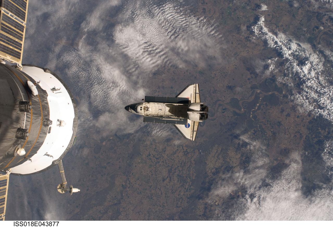 ISS018-E-043877 (25 March 2009) --- Backdropped by a colorful Earth, Space Shuttle Discovery (STS-119) is featured in this image photographed by an Expedition 18 crew member on the International Space Station soon after the shuttle and station began their post-undocking relative separation on March 25, 2009. A portion of a Russian spacecraft docked to the station is at left.