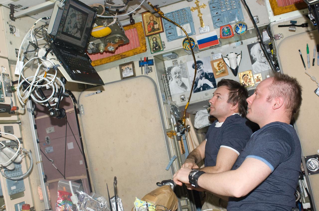 ISS018-E-044033 (26 March 2009) --- NASA astronaut Michael Fincke (foreground), Expedition 18 commander; and cosmonaut Yury Lonchakov, flight engineer, watch a computer monitor in the Zvezda Service Module of the International Space Station showing the Expedition 19 crew and spaceflight participant.