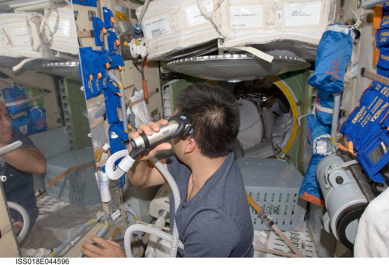 ISS018-E-044596 (4 April 2009) --- Japan Aerospace Exploration Agency (JAXA) astronaut Koichi Wakata, Expedition 18/19 flight engineer, trims his hair in the Zarya module of the International Space Station, using hair clippers fashioned with a vacuum device to garner freshly cut hair.