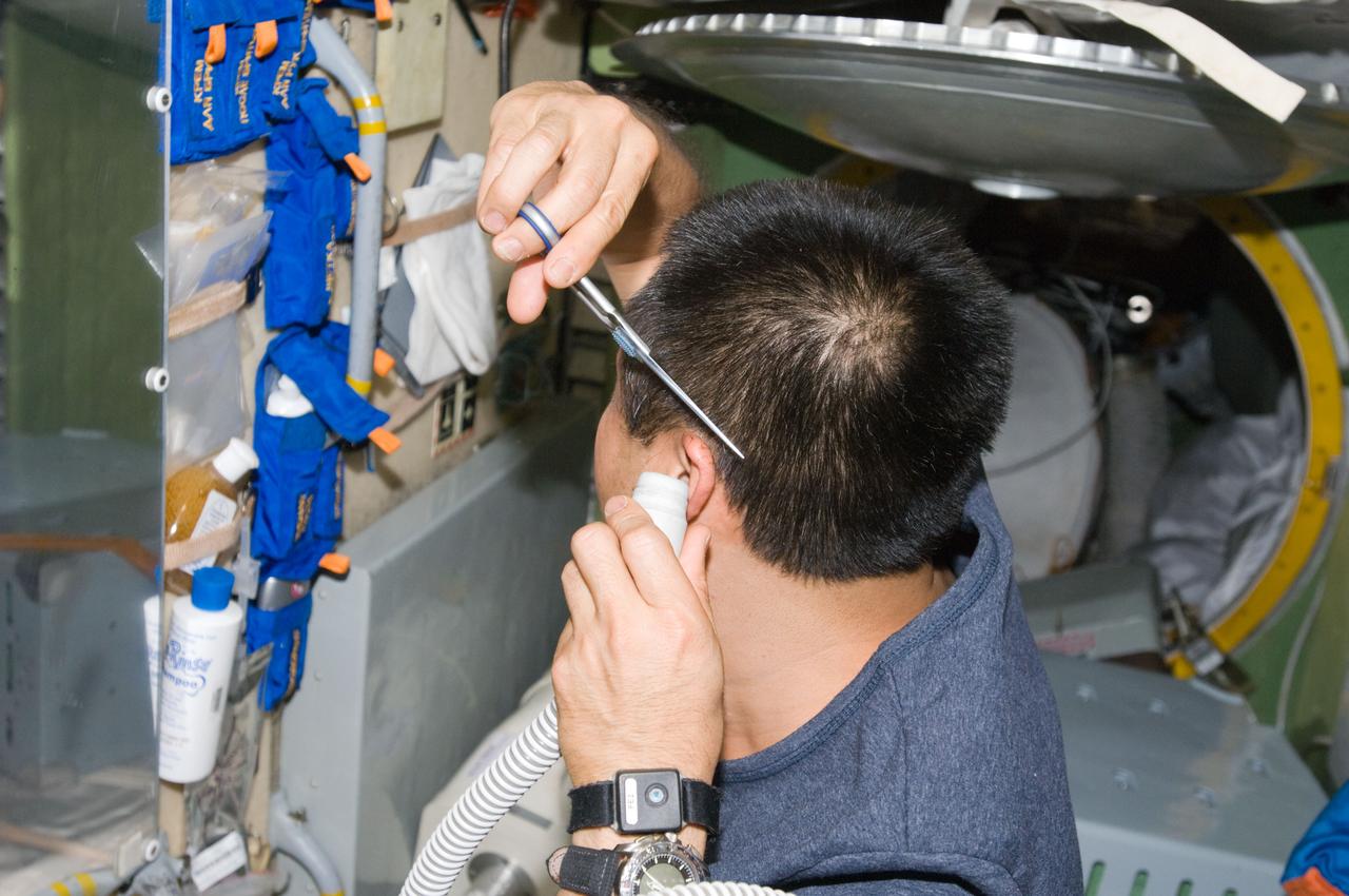 ISS018-E-044602 (4 April 2009) --- Japan Aerospace Exploration Agency (JAXA) astronaut Koichi Wakata, Expedition 18/19 flight engineer, trims his hair in the Zarya module of the International Space Station, using scissors and a vacuum device to garner freshly cut hair.