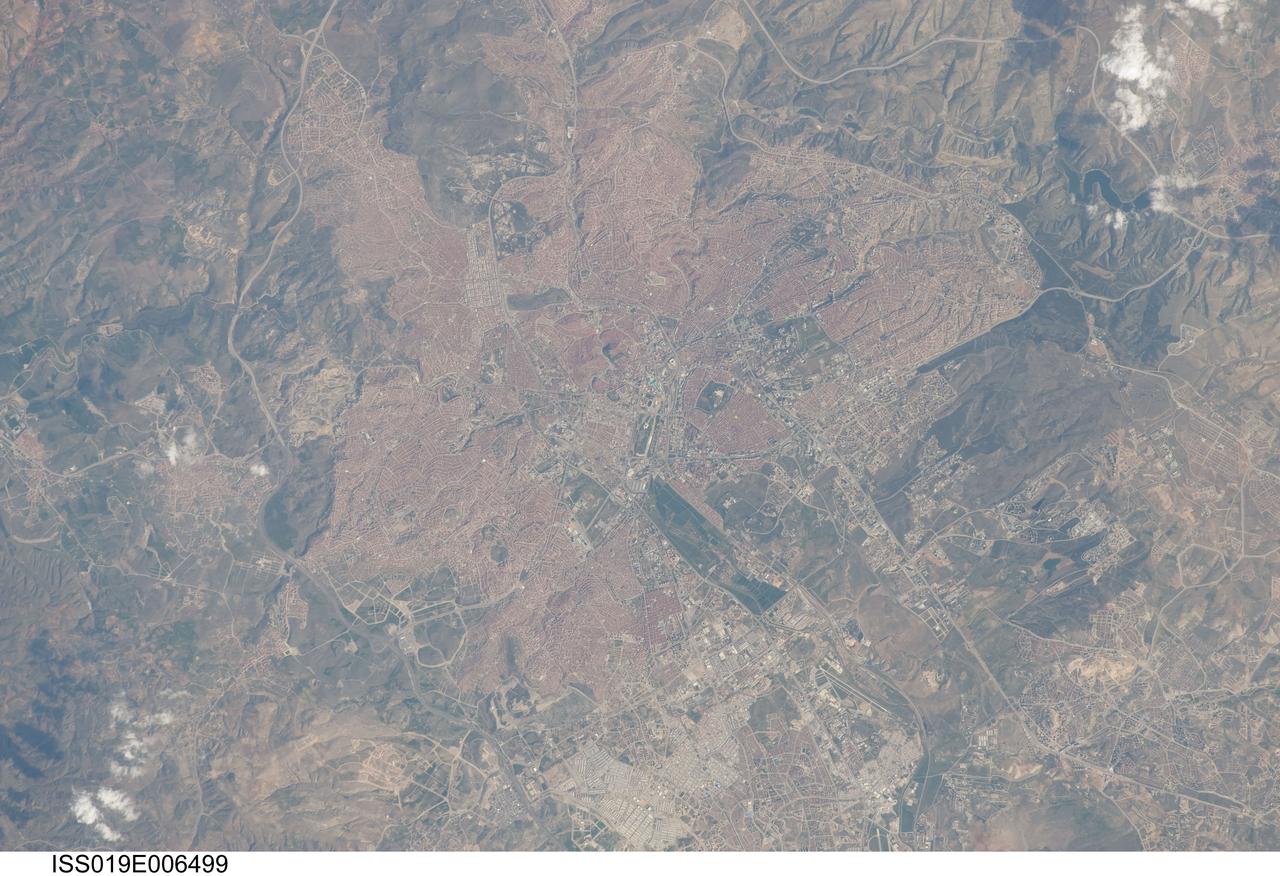 ISS019-E-006499 (11 April 2009) --- Ankara, Turkey is featured in this image photographed by an Expedition 19 crewmember on the International Space Station. The central portion of the capital city of Turkey, Ankara, is featured in this view. Ankara is located in central Turkey ? the climate here is continental and relatively dry, leading to cold winters and hot summers. The region is prone to major earthquakes, as Turkey experiences tectonic forces from both the African plate to the west and the Arabian plate to the east. Despite the earthquake hazard, the city traces its roots back into antiquity, with a Hittite settlement here prior to 1200 BC. A citadel built and occupied in turn by the Galatians, Romans, Byzantines, and Seljuks overlooks the central portion of the city, and today serves as both a historical and recreational site. Perhaps an even more imposing structure - the mausoleum of the founder of the modern-day Republic of Turkey, Mustafa Kemal Ataturk is visible upon an adjacent hill to the southwest. Hillslopes around the city (left and right) are fairly green due to spring seasonal rainfall. One of the most striking aspects of the urban area is the almost uniform use of red brick roofing tiles that contrast with lighter colored road networks ? this is particularly evident in the northern (lower left) and southern (upper right) portions of the city. Numerous park areas are visible as green patches interspersed within the red-tile roofed urban region. A region of cultivated fields in the western portion of the city (center) is a recreational farming area known as the Ataturk Forest Farm and Zoo ? an interesting example of intentional preservation of a former land use within an urban area.