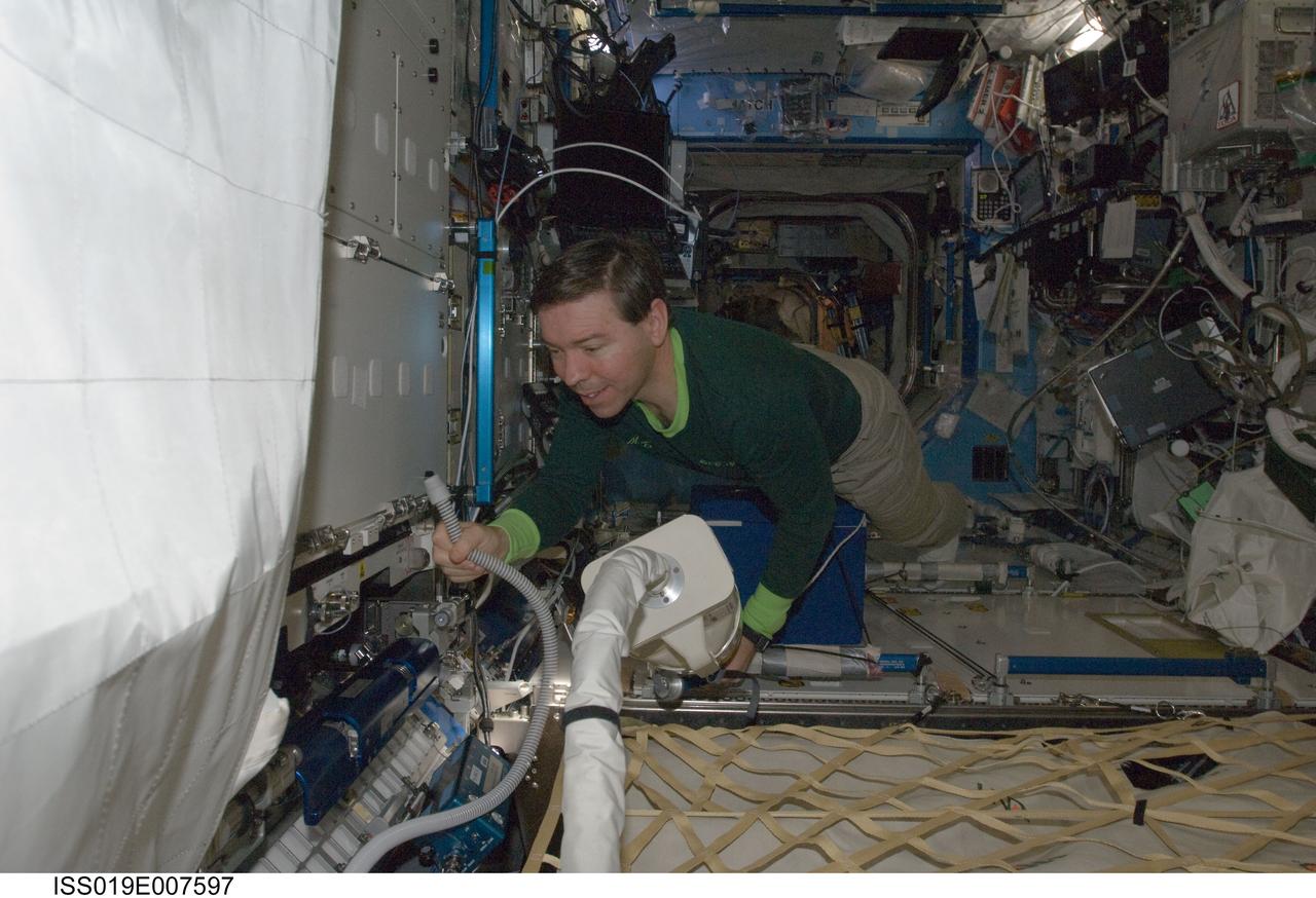 ISS019-E-007597 (18 April 2009) --- Astronaut Michael Barratt, Expedition 19/20 flight engineer, uses a vacuum cleaner during housekeeping operations in the Destiny laboratory of the International Space Station.