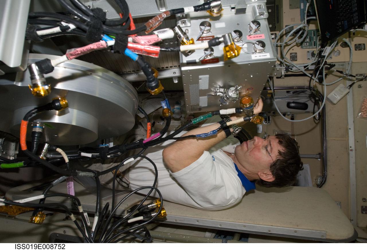 ISS019-E-008752 (21 April 2009) --- Astronaut Michael Barratt, Expedition 19/20 flight engineer, performs in-flight maintenance on the Treadmill Vibration Isolation System (TVIS) in the Zvezda Service Module of the International Space Station.